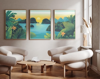 May include: A set of three framed wall art prints featuring a tropical landscape with lush green foliage, orange bird of paradise flowers, blue water, and distant mountains under a yellow sunset sky, displayed in a room with light-coloured furniture.
