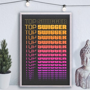May include: A framed print with a black background and white text that reads "TOP SWIGGER" in a gradient of pink, orange, and yellow. The text is repeated multiple times, getting smaller with each repetition.