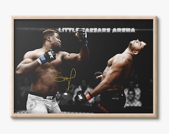 May include: A black and white photograph of two men fighting in a boxing ring. The man on the left is wearing white shorts and a blue and white glove. The man on the right is wearing black shorts and is knocked out. The ring is surrounded by a black fence and the words "Little Caesars Arena" are visible in the background.