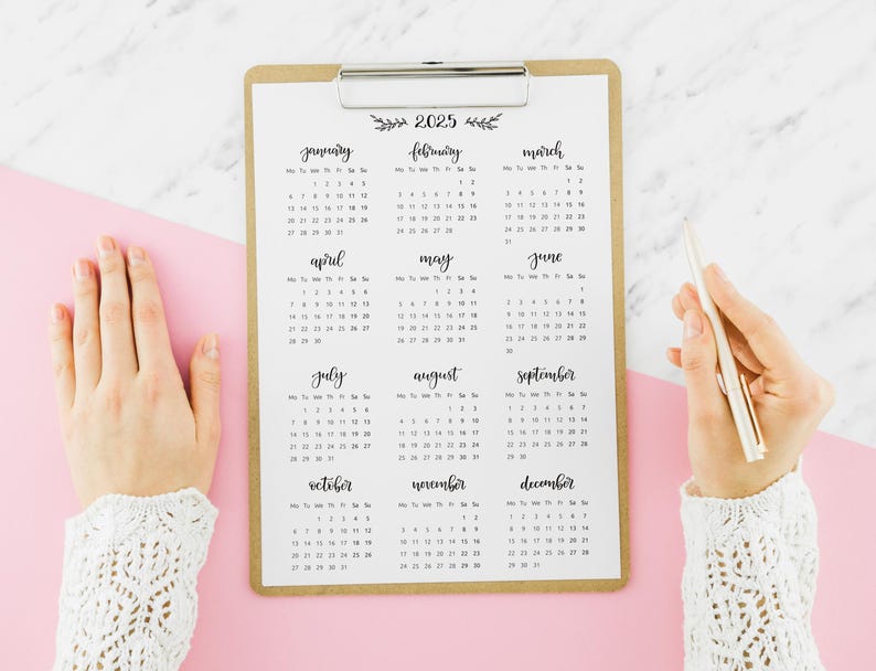 May include: A brown clipboard with a 2025 calendar printed on it. The calendar is divided into 12 months, with each month displayed in a separate box. The months are January, February, March, April, May, June, July, August, September, October, November, and December.