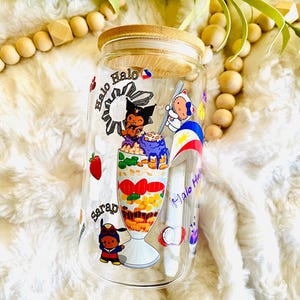 May include: A clear glass jar with a bamboo lid, featuring a colorful illustration of a Filipino dessert called Halo-Halo. The jar has a white background with the words "Halo Halo" and "Sarap" written in purple.