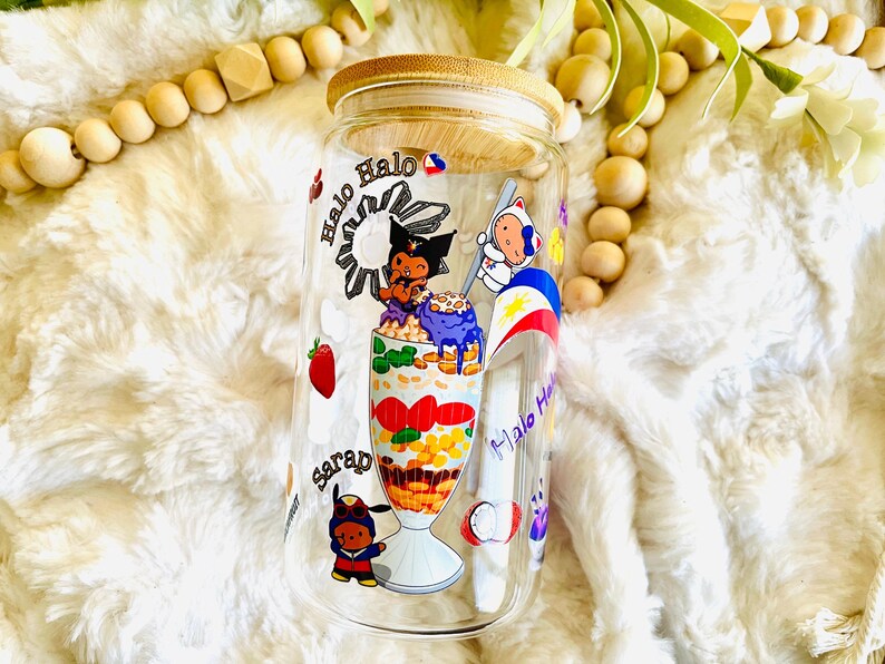 May include: A clear glass jar with a bamboo lid, featuring a colorful illustration of a Filipino dessert called Halo-Halo. The jar has a white background with the words "Halo Halo" and "Sarap" written in purple.