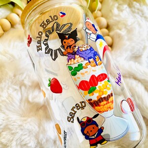 May include: A clear glass bottle with a bamboo lid and a colorful design featuring a cartoon character and the text "Halo Halo Sarap".