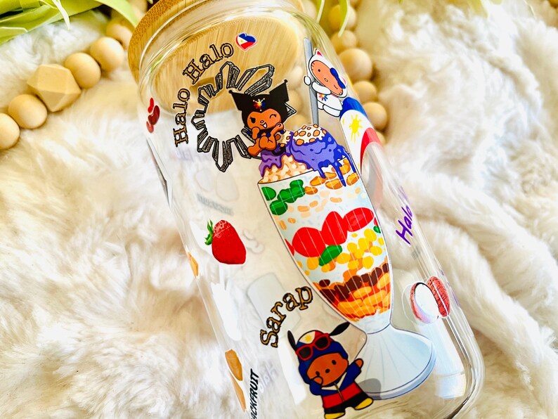 May include: A clear glass bottle with a bamboo lid and a colorful design featuring a cartoon character and the text "Halo Halo Sarap".