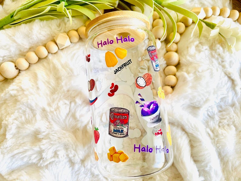 May include: A clear glass jar with a wooden lid and colorful stickers featuring the words "Halo Halo" and images of various ingredients, including jackfruit, ube, and condensed milk.