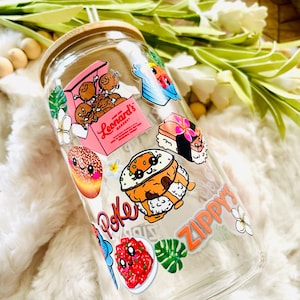 Puede incluir: Una botella de agua reutilizable de vidrio transparente con tapa de bamb&uacute; y una pajita. La botella est&aacute; decorada con pegatinas coloridas que representan comida hawaiana, flores y las palabras "Poke" y "Zippy's".