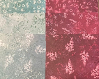 May include: Four squares of patterned paper with a floral design. The top two squares are a light blue color with a white floral pattern. The bottom two squares are a deep red color with a white floral pattern.