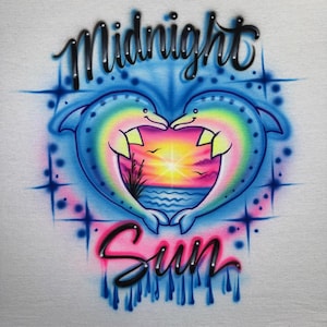 May include: Airbrushed design featuring two dolphins forming a heart shape, with a sunset scene in the center. The words "Midnight Sun" are written above and below the dolphins in a stylized font. The design uses a vibrant color palette of blues, pinks, yellows, and oranges.