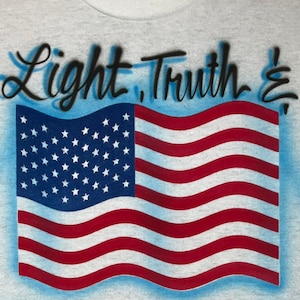 May include: A grey t-shirt with a blue, red, and white American flag design. The text "Light, Truth &" is written in black cursive above the flag.