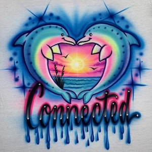 May include: Airbrushed design featuring two dolphins forming a heart shape, with a sunset scene in the center. The dolphins are blue and rainbow-colored, with the word "Connected" in a cursive font below. Blue drips and starbursts complete the design.