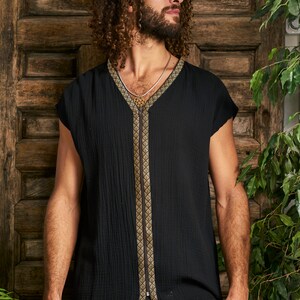 Pode incluir: Uma camisa preta sem mangas com um z&iacute;per dourado e guarni&ccedil;&otilde;es. A camisa tem um decote em V e um caimento solto.