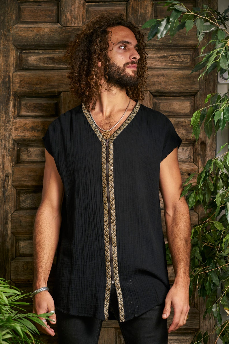 Pode incluir: Uma camisa preta sem mangas com um z&iacute;per dourado e guarni&ccedil;&otilde;es. A camisa tem um decote em V e um caimento solto.