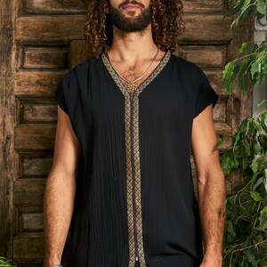 Pode incluir: Uma camisa preta sem mangas com um z&iacute;per dourado e guarni&ccedil;&otilde;es. A camisa tem um decote em V e &eacute; feita de um tecido macio e texturizado.