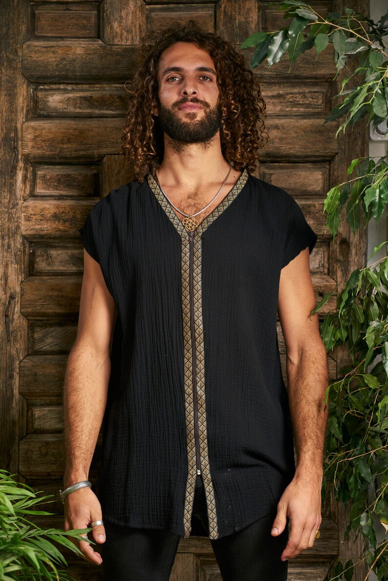 Pode incluir: Uma camisa preta sem mangas com um z&iacute;per dourado e guarni&ccedil;&otilde;es. A camisa tem um decote em V e &eacute; feita de um tecido macio e texturizado.