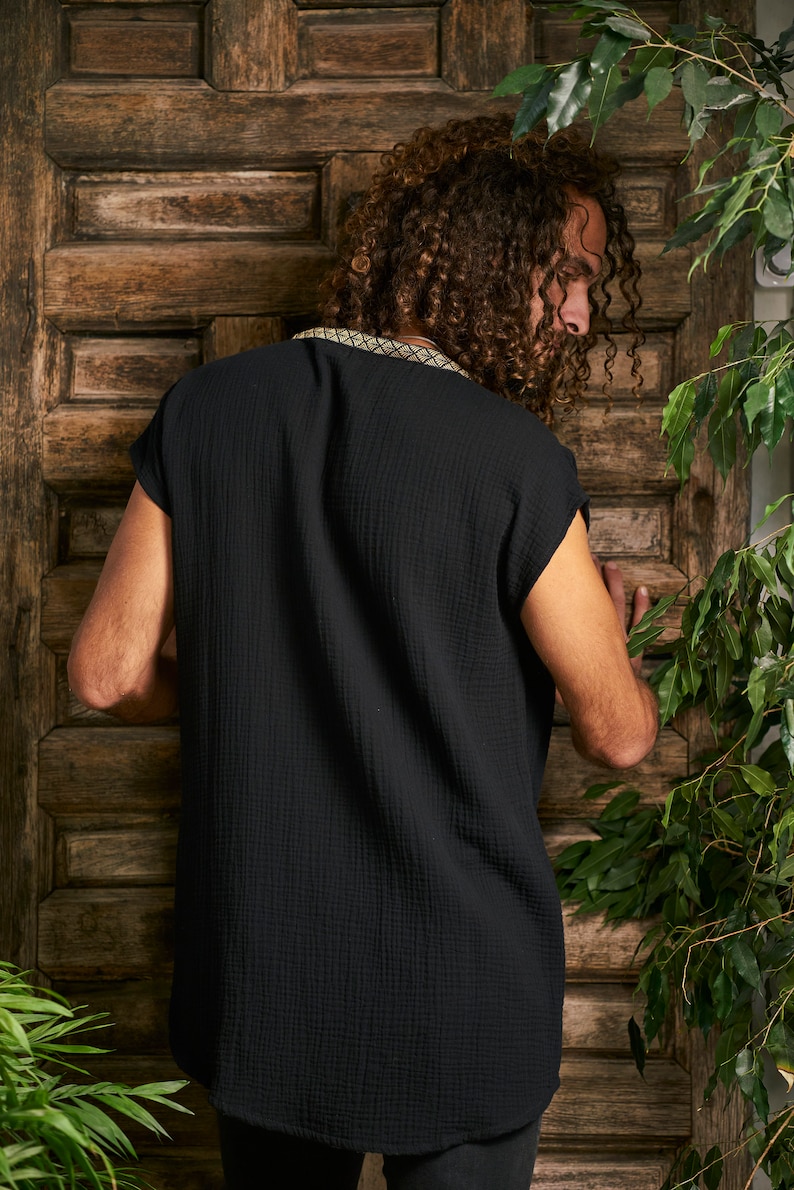 Pode incluir: Uma camisa preta de manga curta com uma guarni&ccedil;&atilde;o decorativa em torno do decote. A camisa &eacute; feita de um tecido macio e texturizado.