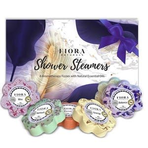 May include: A set of six flower-shaped shower steamers in a box. The steamers are in various colors, including pink, green, yellow, and purple. Each steamer has a label with the name of the scent, such as "Bliss", "Refresh", "Focus", "Energy", and "Balance".