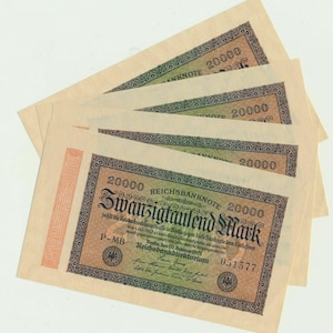May include: A stack of four 20,000 Mark banknotes from 1923. Each rectangular paper bill features a gradient background transitioning from orange to green, black decorative borders, and the text "Zwanzigtausend Mark" and "Reichsbanknote".