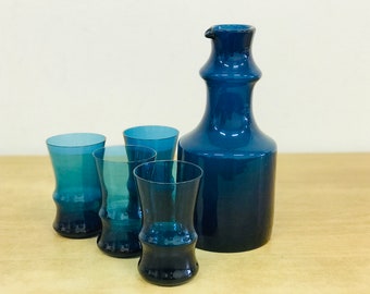 May include: A set of four blue glass drinking glasses and a matching blue glass decanter.