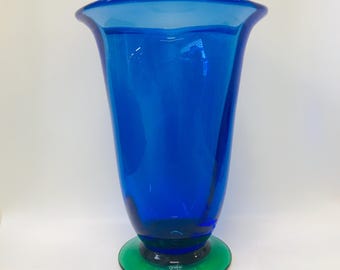 Könnte beinhalten: Eine kobaltblaue Glasvase mit einem ausgestellten oberen Rand und einem grünen Sockel. Die Vase ist unten mit "Orrefors Sweden" gekennzeichnet.