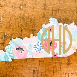 Op de afbeelding: Een vinyl sticker met een bloemenpatroon van de staat Kentucky met een gouden monogram in het midden. Het monogram bestaat uit de letters "AHD".