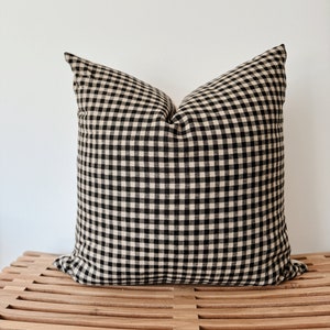 May include: Black and white gingham pillow on a wooden bench.