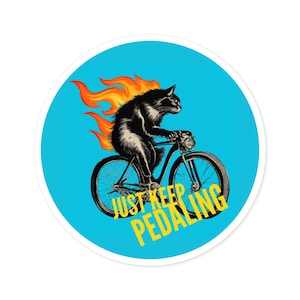 May include: A black cat on fire riding a bicycle with the text "Just Keep Pedaling" in yellow on a blue background.