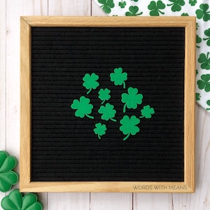 May include: A black felt letter board with a wooden frame, decorated with green shamrock cutouts. The board has the text "WORDS WITH MEANS" printed on the bottom.