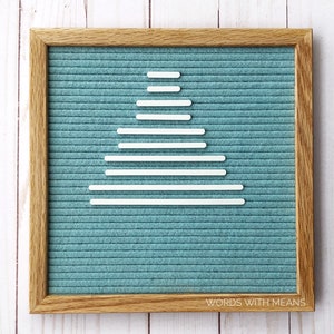 May include: A teal felt letter board with a white, stylized Christmas tree design made of horizontal lines. The board is framed in natural wood and has the text "WORDS WITH MEANS" at the bottom.