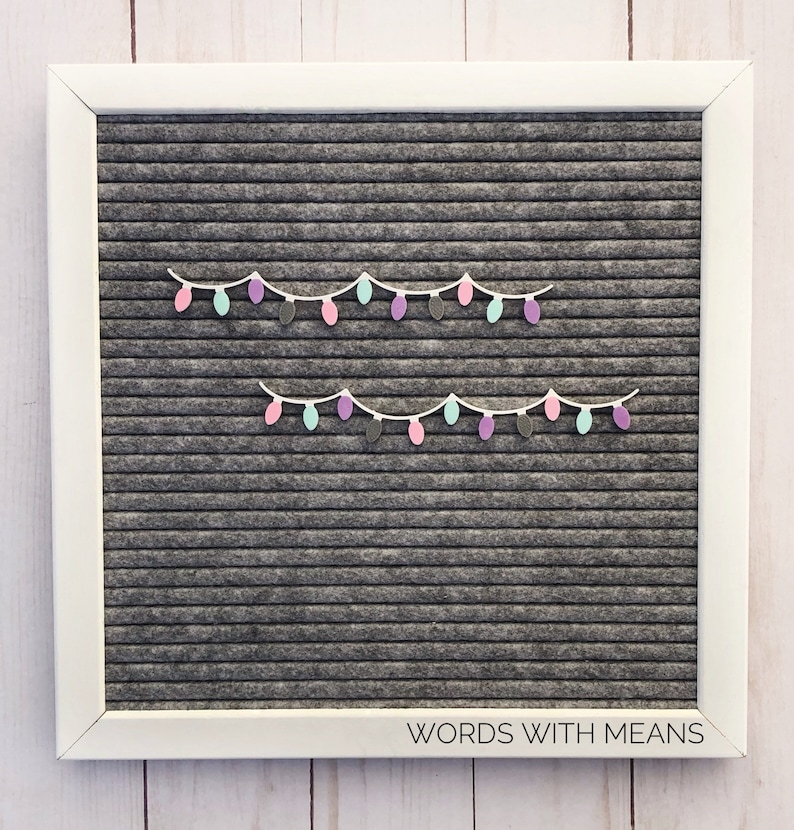 May include: A gray letter board with two strings of pastel colored paper lightbulbs. The board has the words "WORDS WITH MEANS" printed on the bottom.