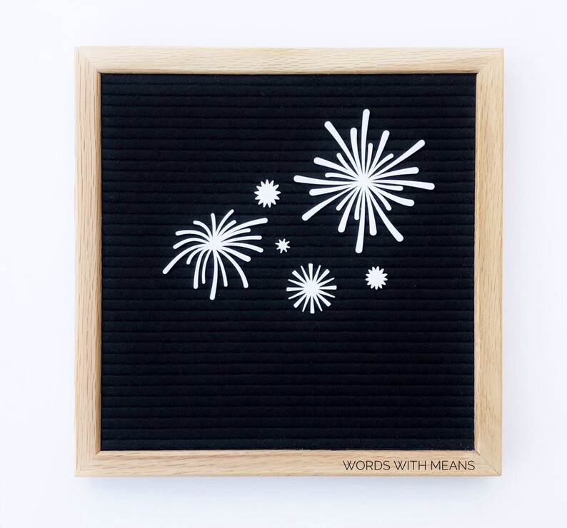 Puede incluir: Un tablero de letras negro con un marco de madera y letras de fieltro blanco que deletrean "WORDS WITH MEANS". El tablero est&aacute; decorado con recortes de papel blanco en forma de fuegos artificiales.