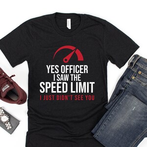 May include: Black t-shirt with a white graphic of a speedometer with a red needle. The text on the shirt reads "Yes Officer I saw the speed limit I just didn't see you."