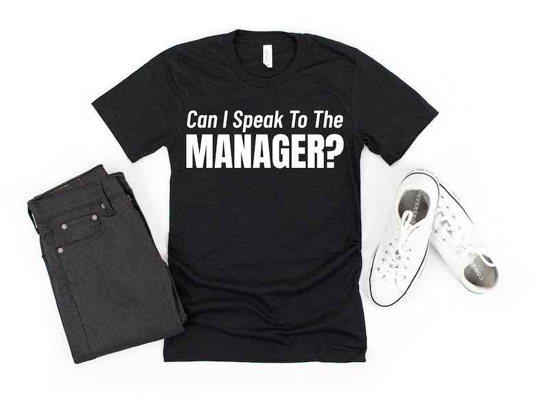 May include: Black t-shirt with white text that reads "Can I Speak To The MANAGER?"