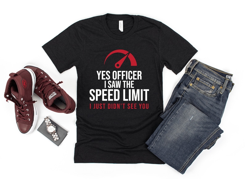 May include: Black t-shirt with a white graphic of a speedometer with a red needle. The text on the shirt reads "Yes Officer I saw the speed limit I just didn't see you."
