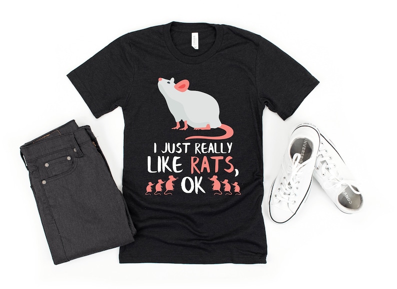 May include: Black t-shirt with a white rat illustration and the text "I just really like rats, ok". The shirt has a crew neck and short sleeves. There are also smaller rat illustrations below the text.