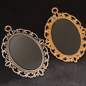 May include: Two ornate silver and gold oval picture frames with black backgrounds. The frames have intricate designs and are perfect for adding a touch of elegance to any project.