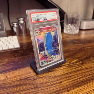 Puede incluir: Una carta Pokémon calificada con Wailord, una ilustración rara del set JTG EN 2025. La carta está dentro de un soporte protector transparente y se muestra en un soporte negro. Detalles: número 162 y calificación NM-MT 8.