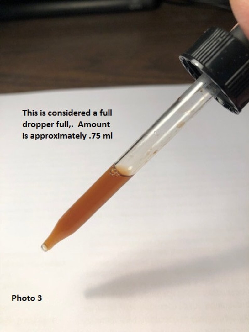May include: A clear glass dropper with a brown liquid inside. The dropper is full and the text "This is considered a full dropper full. Amount is approximately .75 ml" is visible below the dropper. Photo 3 is also visible in the image.