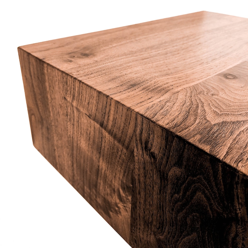 May include: A solid, rectangular wooden block with a rich, dark brown color and visible wood grain. The block's surface is smooth and polished, with a slight sheen. The edges are clean and sharp, suggesting a modern design. This could be a coffee table or a decorative element.