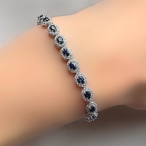 May include: A silver bracelet with a row of oval-shaped blue gemstones surrounded by smaller white gemstones.