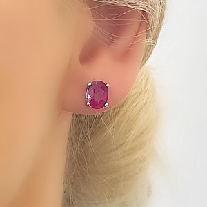 Peut inclure: Une paire de boucles d'oreilles en forme de rubis ovales serties d'argent. Les boucles d'oreilles sont présentées sur l'oreille d'un mannequin.