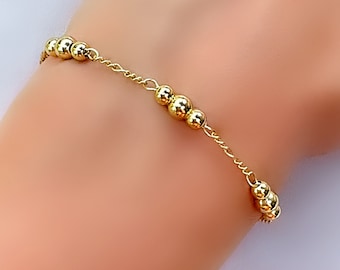 May include: A gold beaded bracelet with a delicate chain. The bracelet features a series of small, round beads.