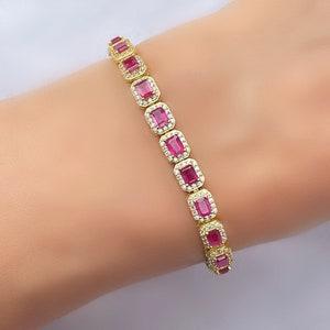 Puede incluir: Una pulsera de oro con una fila de piedras rectangulares rosas engastadas en un halo de piedras transparentes más pequeñas.