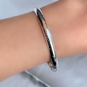 Peut inclure: Un bracelet jonc en argent avec un motif texturé. Le bracelet est porté au poignet.