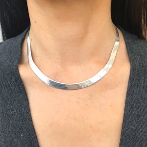 May include: A silver chain necklace with a herringbone pattern.