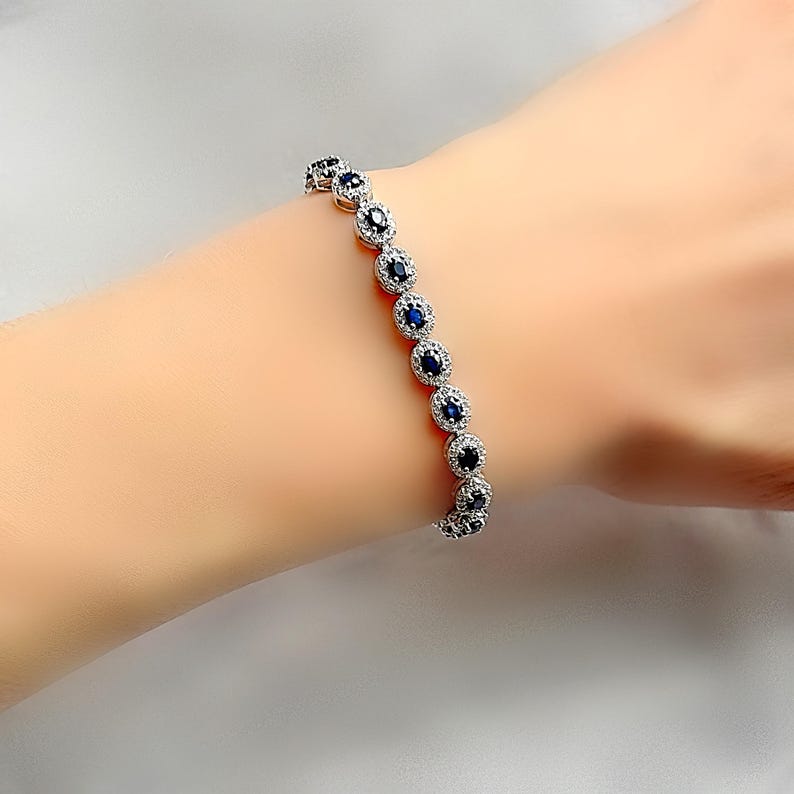 May include: A silver bracelet with a row of oval-shaped blue sapphires surrounded by smaller white diamonds.