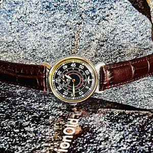 May include: A vintage wristwatch with a black dial and gold-tone case. The watch features a brown leather strap. The dial displays numerals and hands for timekeeping. The watch is a classic accessory.