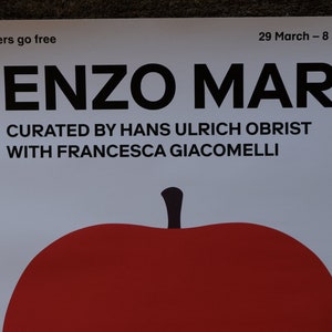 Op de afbeelding: Een witte poster met zwarte tekst die "Members go free", "29 March - 8 September", "ENZO MARI", "CURATED BY HANS ULRICH OBRIST" en "WITH FRANCESCA GIACOMELLI" zegt. Een rode appel met een zwarte steel bevindt zich onderaan de poster.