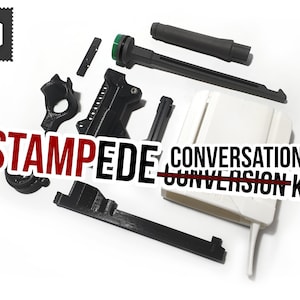 May include: A disassembled black and white conversion kit with the word "STAMPEDE" in red and the text "CONVERSION KIT" in white. The kit includes various plastic components, including a long barrel, a handle, and several smaller pieces.