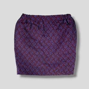 May include: A purple and burgundy skirt with a geometric pattern. The skirt has a waistband and is made of a textured fabric.