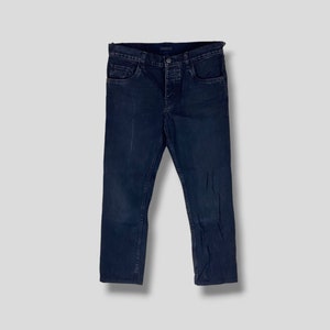 Pode incluir: Jeans de denim azul escuro com fecho de botão e cinco bolsos.